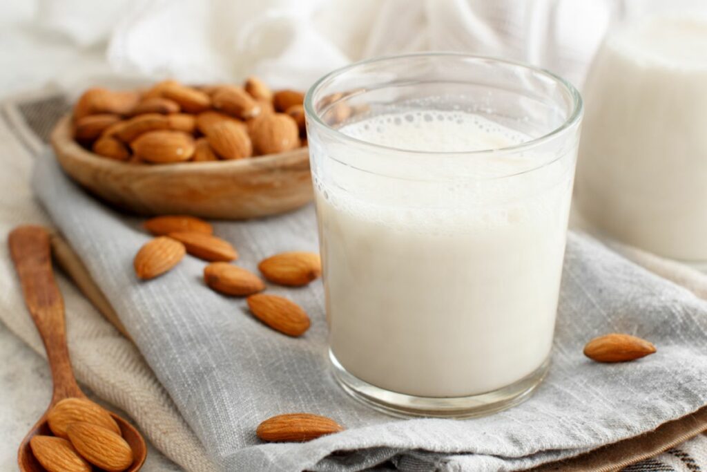 a glass of almond milk with some almonds next to it