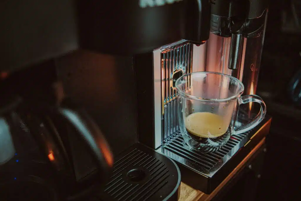 a glass of liquid on a clean coffee machine