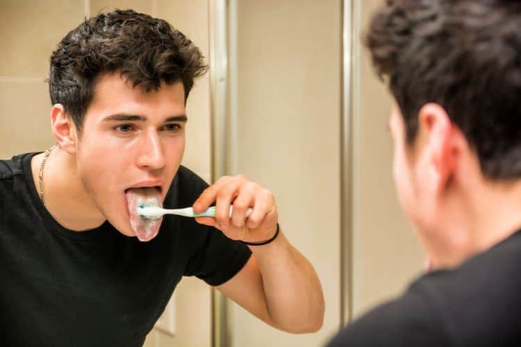 Young man brushing his tongue