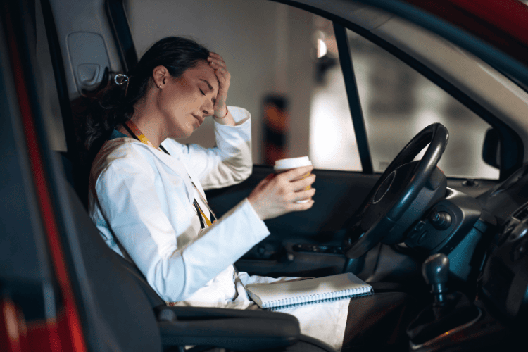 Woman in car driver's seat with head on hand, looking nauseous from coffee